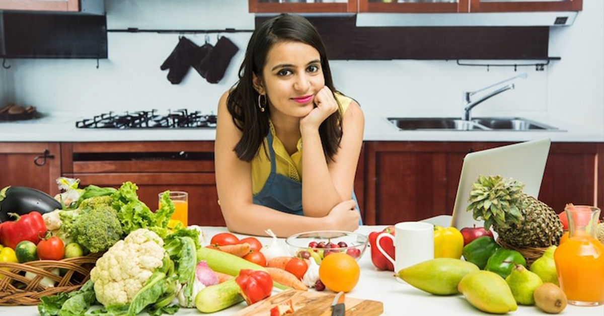 A women along with a variety of vegetables and fruits on the table